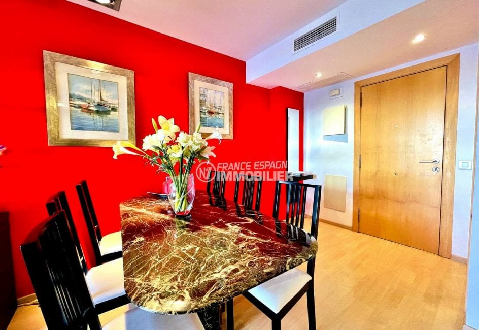 appartement à vendre à rosas espagne, 2 chambres 74 m², séjour avec grande table et 6 chaises, lithographies au mur
