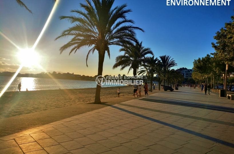 coucher de soleil sur la plage de roses santa margarita avec ses palmiers et ses terrasses de restaurants